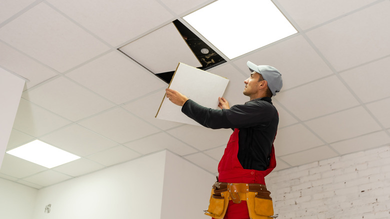 A person installs a drop ceiling