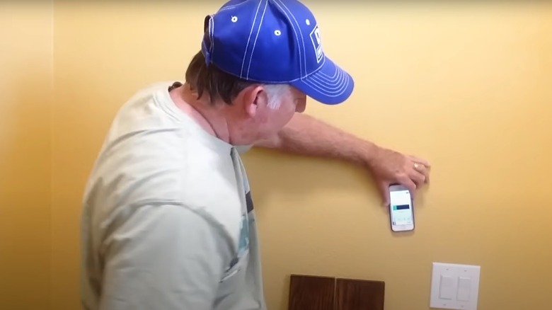 man holding smartphone stud finder app