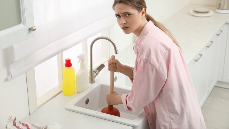 Concerned woman plunging kitchen sink