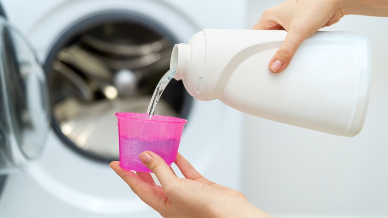 Hand pouring laundry detergent