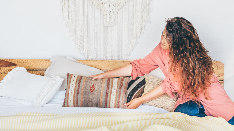 woman arranging pillows on bed