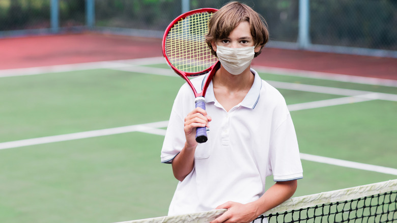 masked boy on tennis court