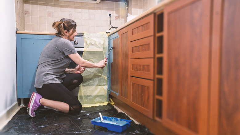 Homeowner painting cabinets to renovate kitchen