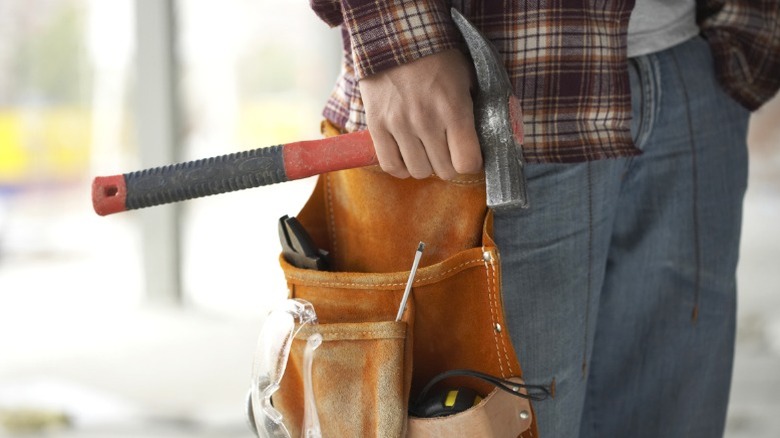 man with toolbelt on holding hammer