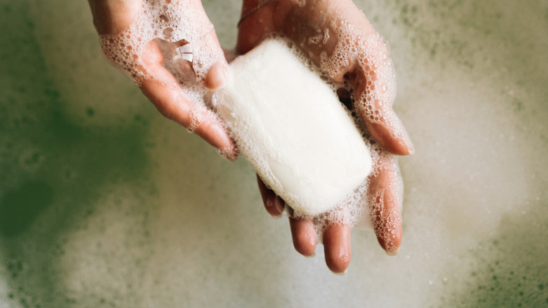 Hand holding a bar of soap with suds