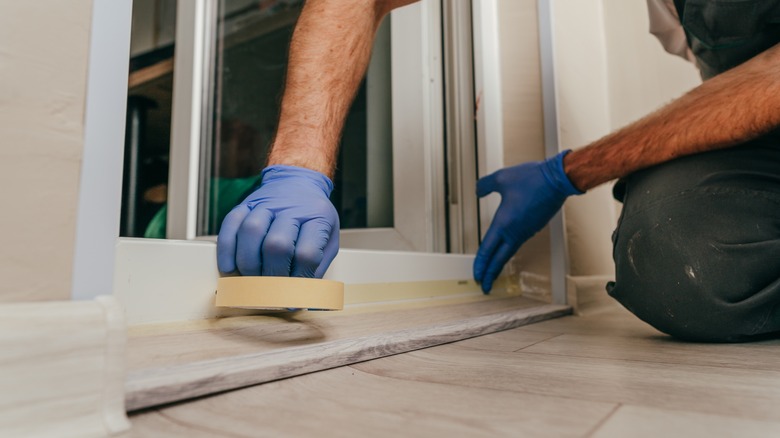 man using tape to apply caulk