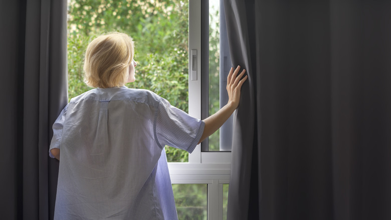 Woman opening blackout curtains