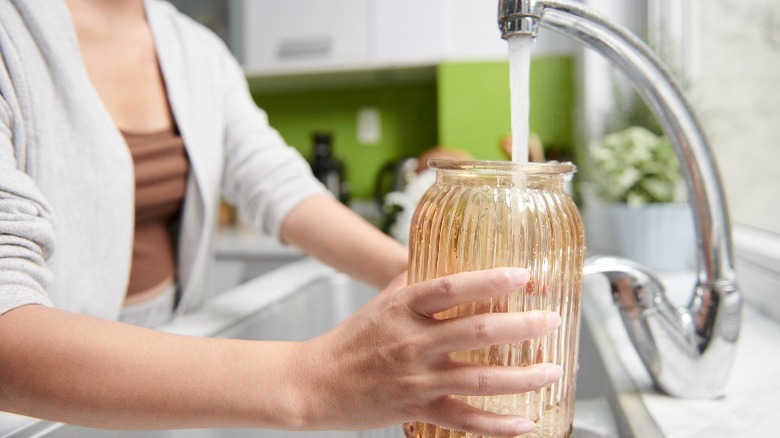 Woman filling vase with tap water 