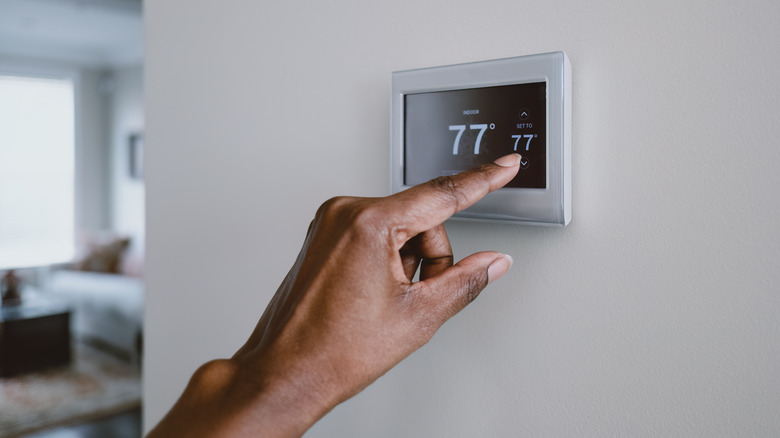 A hand adjusting the temperatue on a thermostat