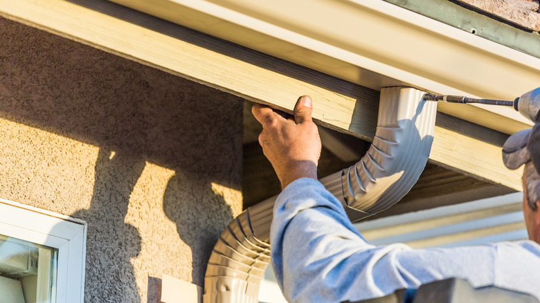 man installing gutter downspout