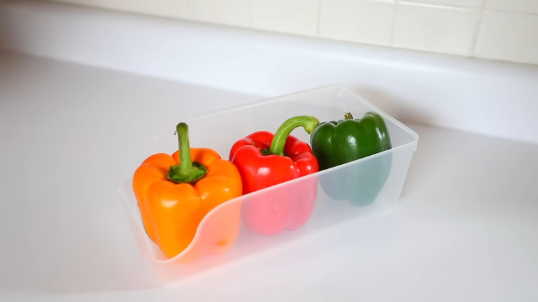 Red, orange, and green bell pepper in a plastic soda holder on the counter