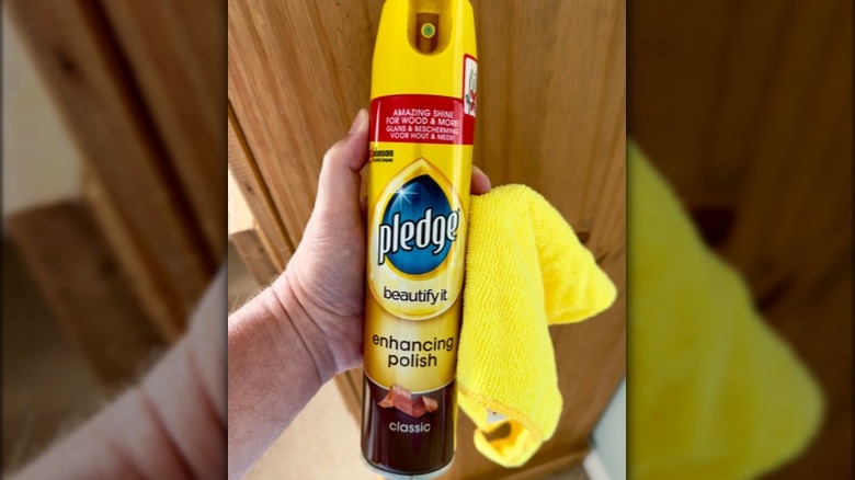 A person holds a bottle of Pledge furniture polish