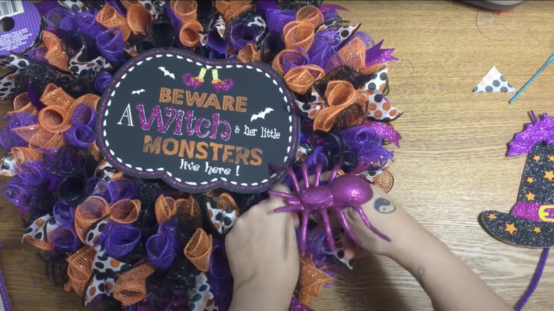 hands making Halloween wreath