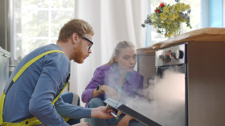 woman showing repairman broken oven