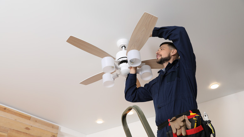 young electrician installing ceiling fan