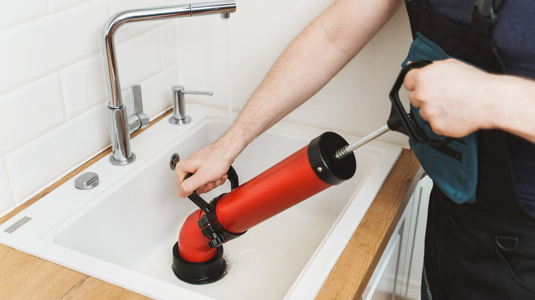 A plumber unblocking a sink drain 