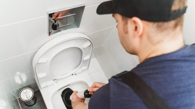 A plumber unblocking a toilet 