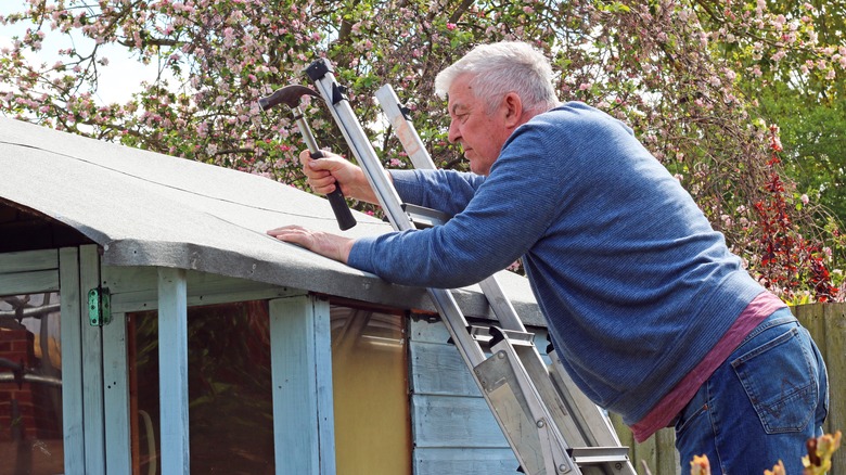 man repairing outdoor shed