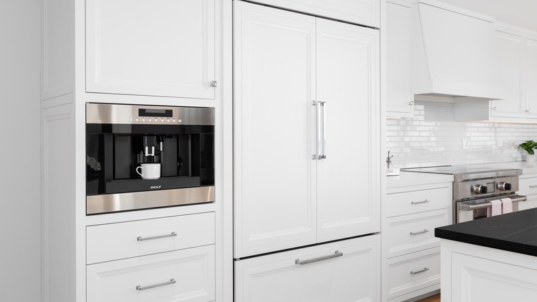 A built-in coffee maker inside a white kitchen