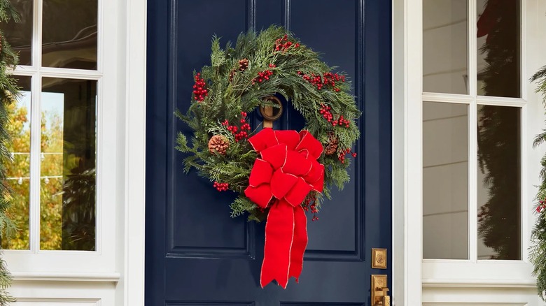 Big red bow on a wreath mounted on a front door