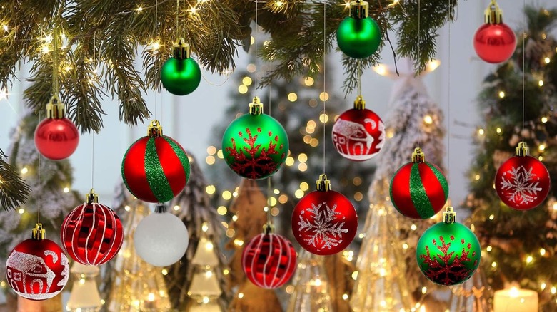 Bright red and green Christmas ornaments hanging from a tree