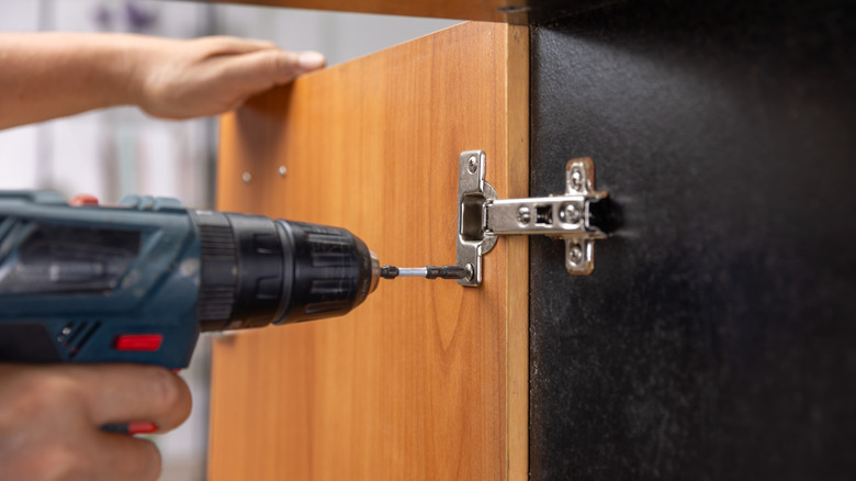 Hinges being drilled onto a cabinet door