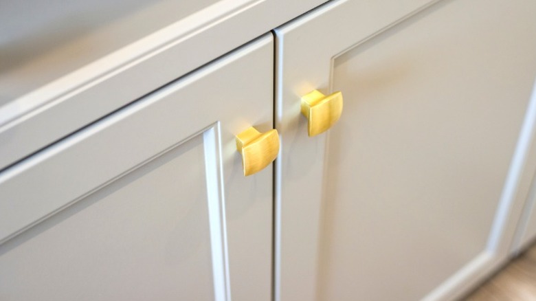 White double door cabinet with square gold knobs