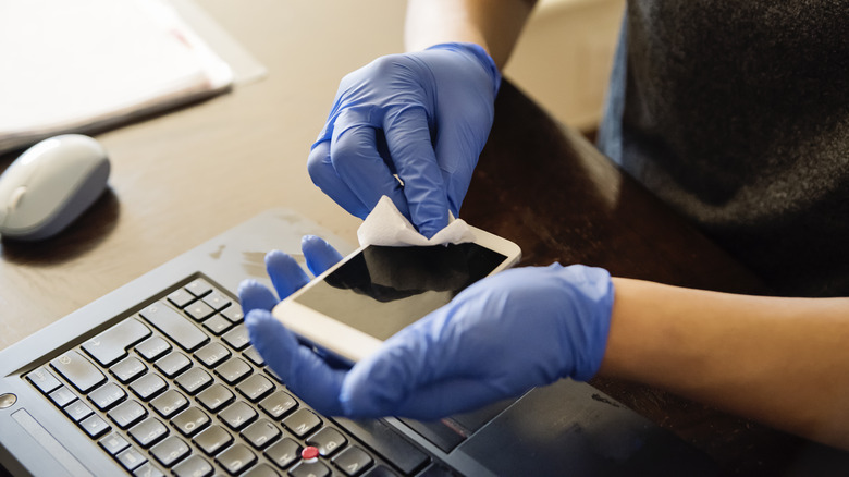 Person sanitizing mobile phone