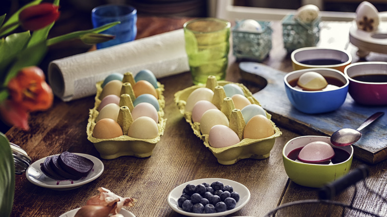 Array of Easter eggs being dyed on a wood countertop or table