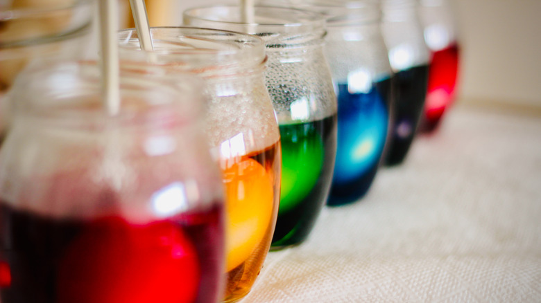 Jars of colorful dye with eggs inside on a counter or table