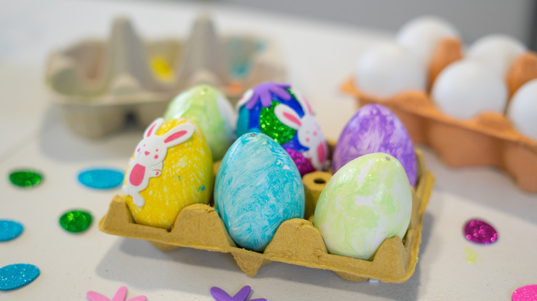 Easter eggs decorated with glitter and stickers inside an egg carton