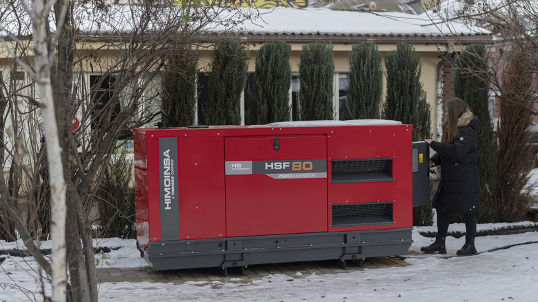 woman checking generator in snow 