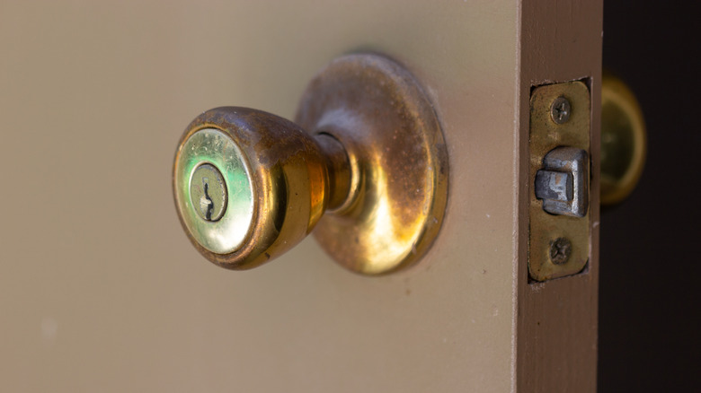 Dirty brass doorknob on white door