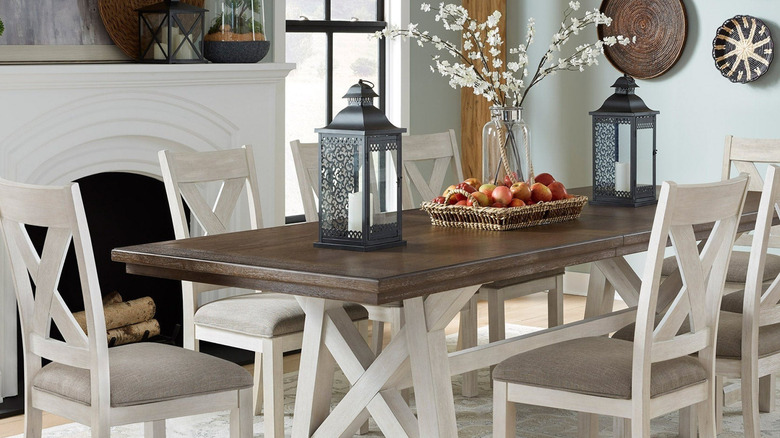 Nine piece dining set with apples, candles, and flowers on the table.