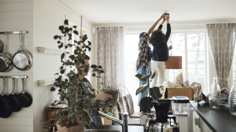 People trying to hang a pendant light fixture