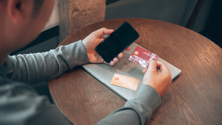 A person holding a smartphone and a credit card