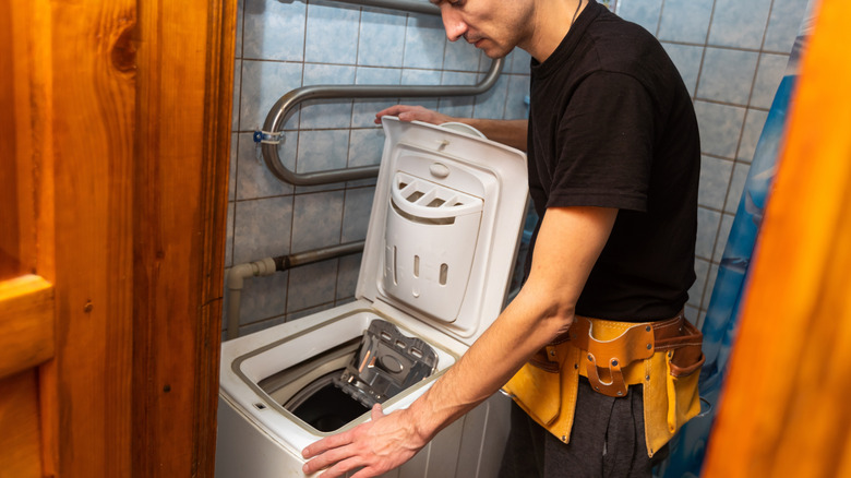 A person is trying to repair an old washing machine