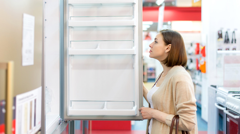 A woman inspecting a new refrigerator in the store