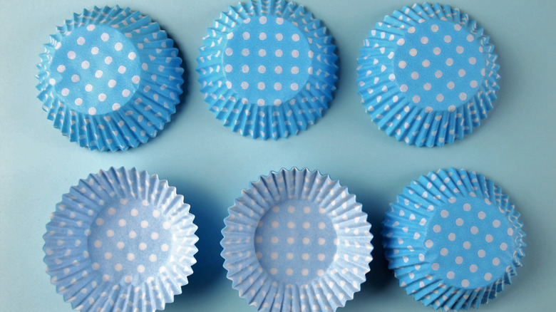 Two rows of blue and white polka dot cupcake wrappers on a light grey-blue background