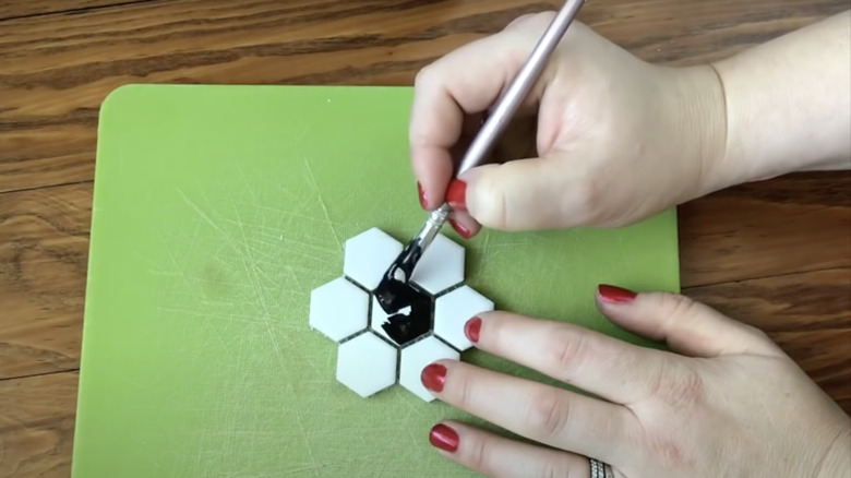 woman painting her hexagonal tiles