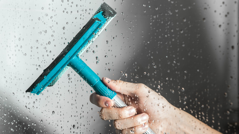 person cleaning with blue squeegee