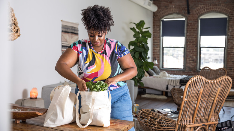 woman unpacking reusable grocery bags