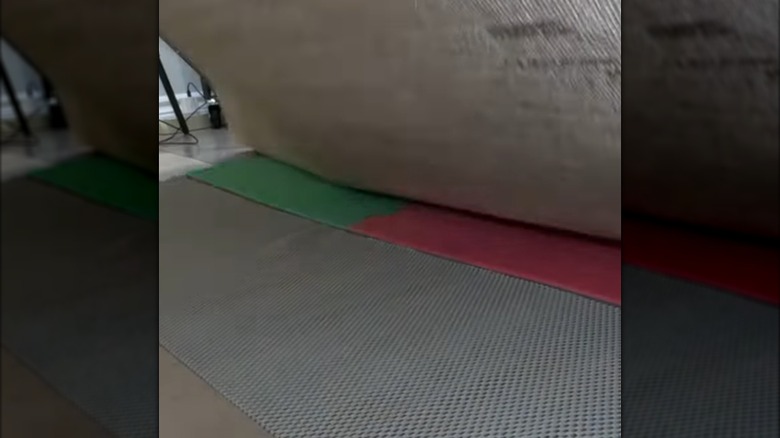 Placing gray shelf liner underneath rug