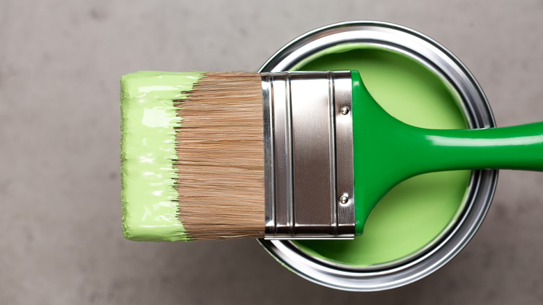 A used paint brush lying across the top of an open container