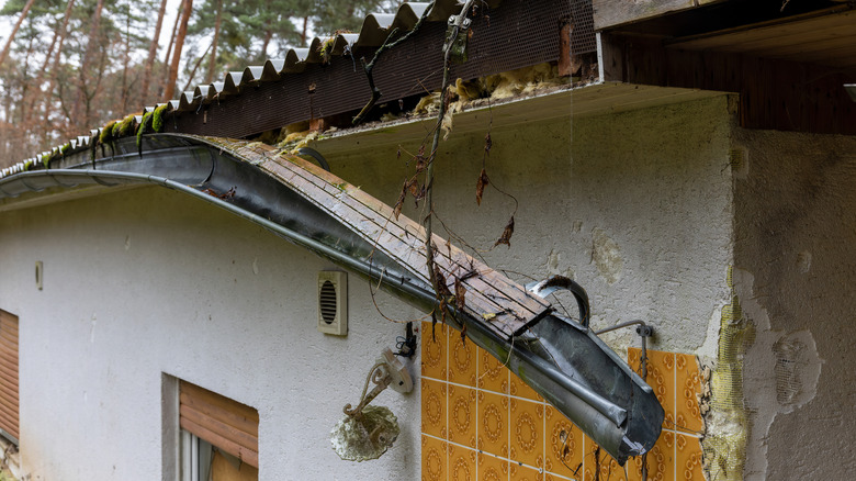 A section of rain gutter is detaching from the roof of an old house.