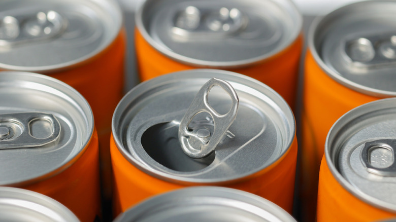 Close-up image of orange aluminum cans, with one open in the middle.