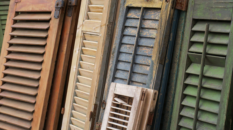 Collection of old wooden window shutters leaning against a wall