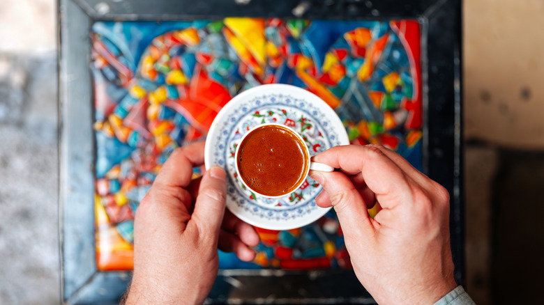 teacup held above mosaic table