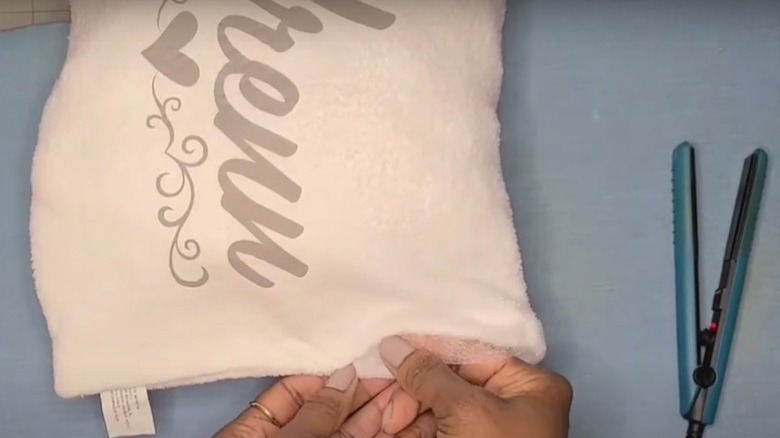 A woman holds the cushion she has crafted from microfiber cloth.