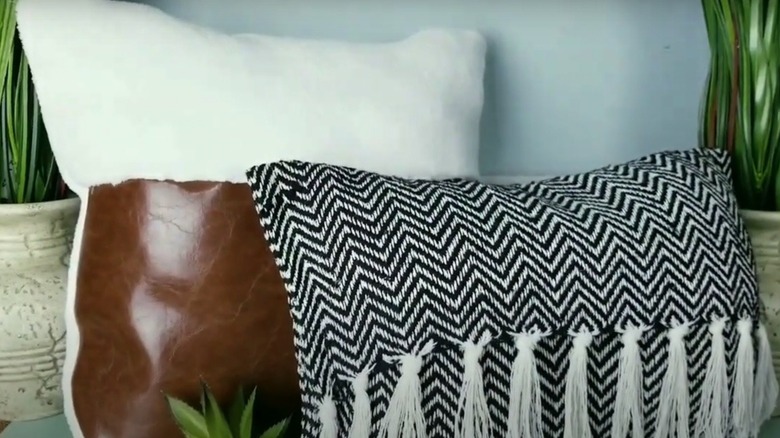 A cushion cover made from faux leather, microfiber cloth, and decorative fringe